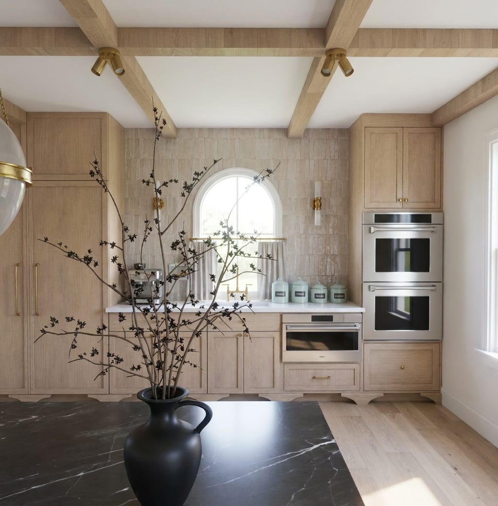 Kitchen cabinetry, arched window, and dark stone island designed by Carolpe Designs